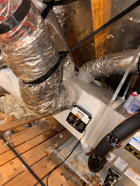HVAC ductwork wrapped in foil insulation with equipment and tools on wooden floor